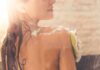 Woman showering with loofah on shoulder