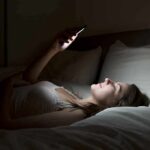 Cancer WARNING: Bad Sleepers Beware Woman lying in bed looking at smartphone