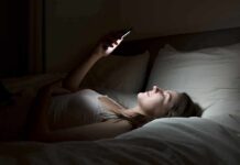 Woman lying in bed looking at smartphone