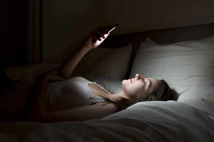 Woman lying in bed looking at smartphone