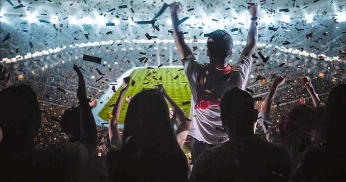 Fans celebrate in a packed stadium with confetti falling