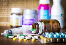 Telehealth Pill Mills – The future of medicine? Medicine pills and syringe on table with brown bottle