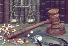 Gavel with scales, pills, and stethoscope on a desk