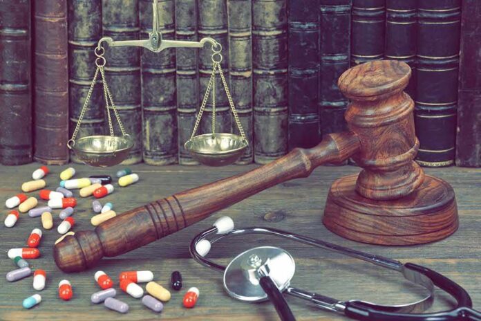 Gavel with scales, pills, and stethoscope on a desk