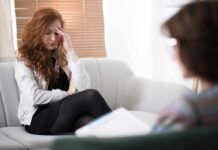 Woman with hand on forehead sitting on couch during counseling session