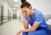 Nurse in blue scrubs sitting with head in hand
