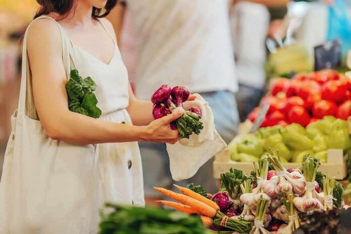 Woman selecting fresh vegetables at a farmers market stall