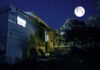 RV under a full moon at a forest campsite