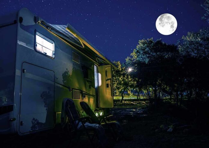 RV under a full moon at a forest campsite