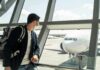 Traveler wearing a mask looks at airplane through airport window