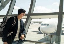 Traveler wearing a mask looks at airplane through airport window