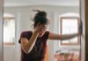 Woman holding her head and steadying herself in a blurred room