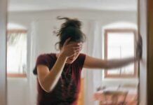 Woman holding her head and steadying herself in a blurred room