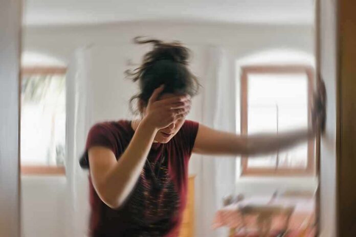 Woman holding her head and steadying herself in a blurred room