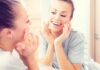 Woman smiling at her reflection in a bathroom mirror