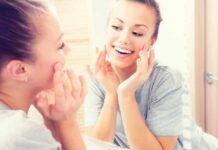 Woman smiling at her reflection in a bathroom mirror