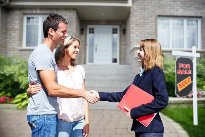 Homebuyers shaking hands with real estate agent outside house