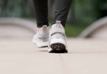 Close-up of person walking in gray sneakers