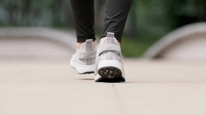 Close-up of person walking in gray sneakers