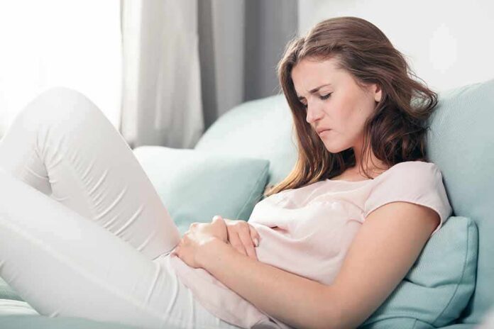 shutterstock_436068577 Woman lying on couch holding her stomach