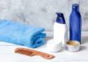 bathroom toiletries with blue towel and wooden comb on white surface