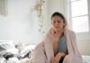 Woman wrapped in blanket touching her throat