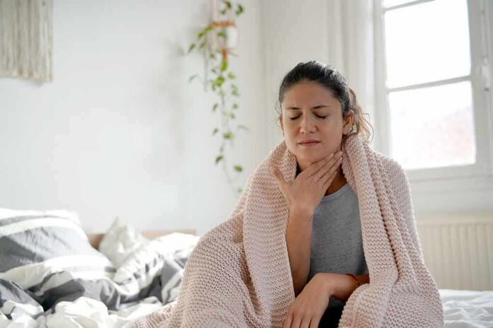 1783890014815-0uzxvx-shutterstock-1257992872 Woman wrapped in blanket touching her throat
