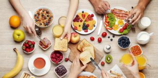 Breakfast table with assorted foods and hands serving