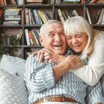 Older couple hugging and laughing on a couch