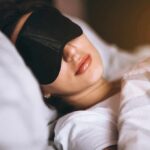 Eight-Hour Sleep Myth? Scientists Flip The Script Woman sleeping with a black eye mask in bed