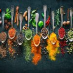 Assorted spices in vintage spoons on dark background