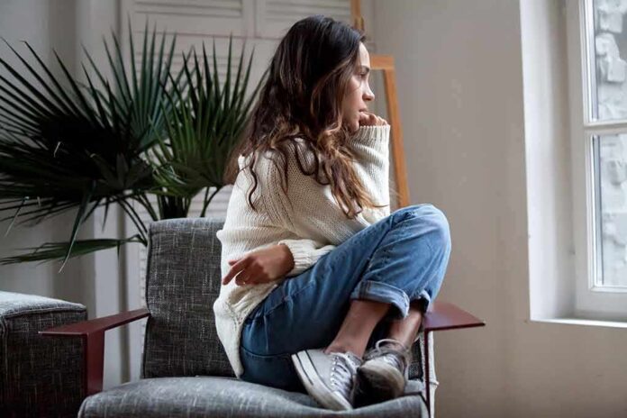Woman sitting curled up on a chair looking out a window