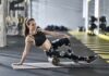 Woman foam rolling thigh on yoga mat in gym