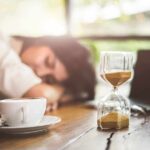 No-Wearable Sleep Tracking Arrives Hourglass on table with coffee cup and sleeping person in background