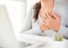 person clutching chest with both hands at a desk