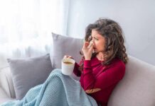 Woman on couch with tissue and mug