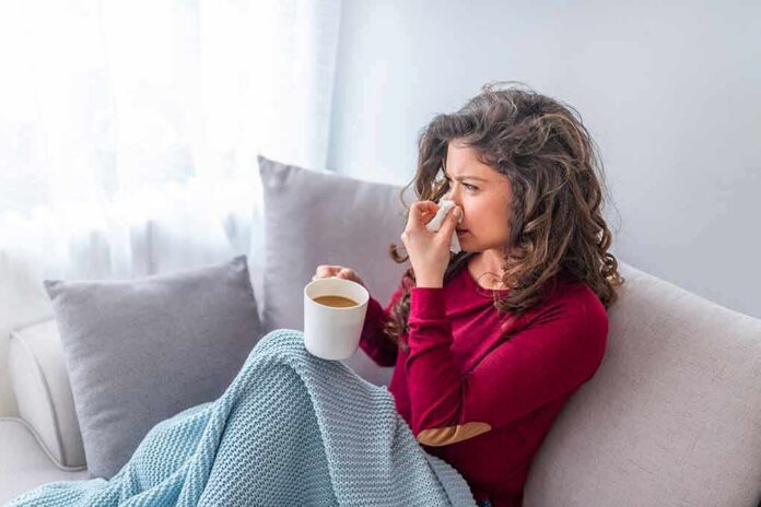 Woman on couch with tissue and mug