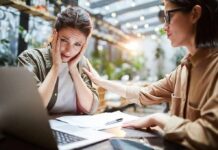 Two women at a table, one comforting the other