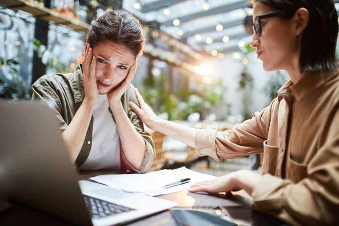 Two women at a table, one comforting the other