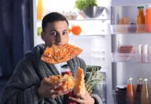 Night Cravings Explained – Why 8 P.M. Appetite Spikes man in robe eating pizza at open refrigerator