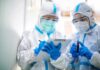 CDC Eyes Russia: 200 Watched After Deadly Biolab Disaster Two healthcare workers in full PPE reviewing a clipboard