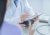 Doctor writing on clipboard during patient consultation
