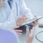 Early Signs of Cancer Most Young People Ignore Doctor writing on clipboard during patient consultation