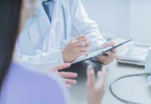 Doctor writing on clipboard during patient consultation