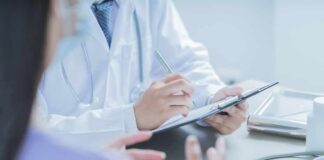 Doctor writing on clipboard during patient consultation