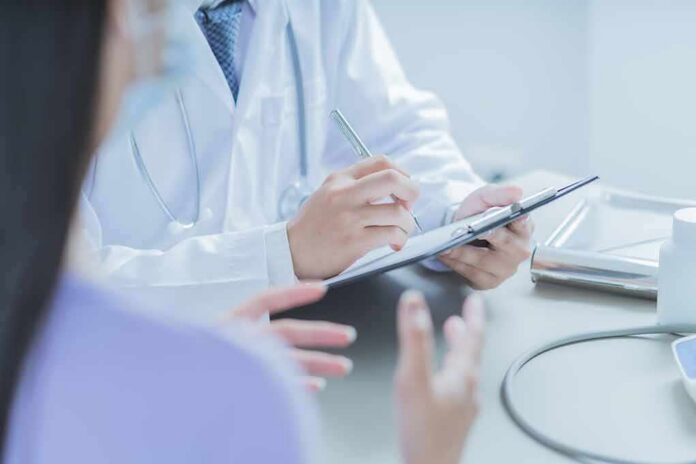 Doctor writing on clipboard during patient consultation