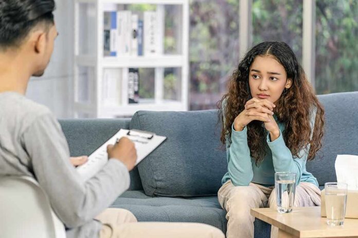 shutterstock_1898082823 Young woman sitting on couch during counseling session