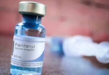 Fentanyl vial on a table with blurred syringe in background