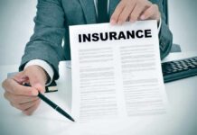 Health Costs To SURGE – Brace For 2027 Person in suit holding an insurance document and a pen
