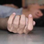 Close-up of a hand on the floor with person lying in background